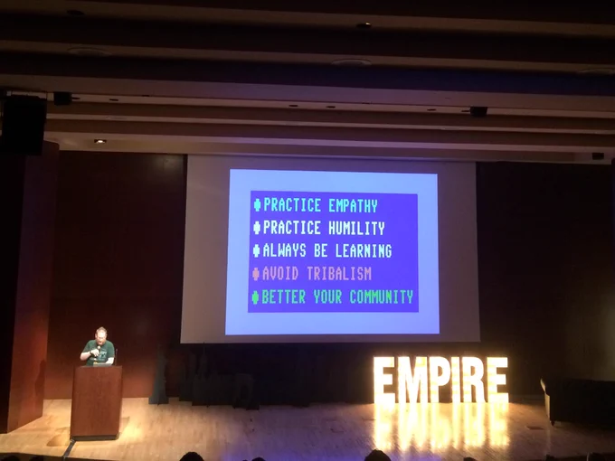 Picture of speaker and slide saying "Practice empathy, practice humility, always be learning, avoid tribalism, better your community"
