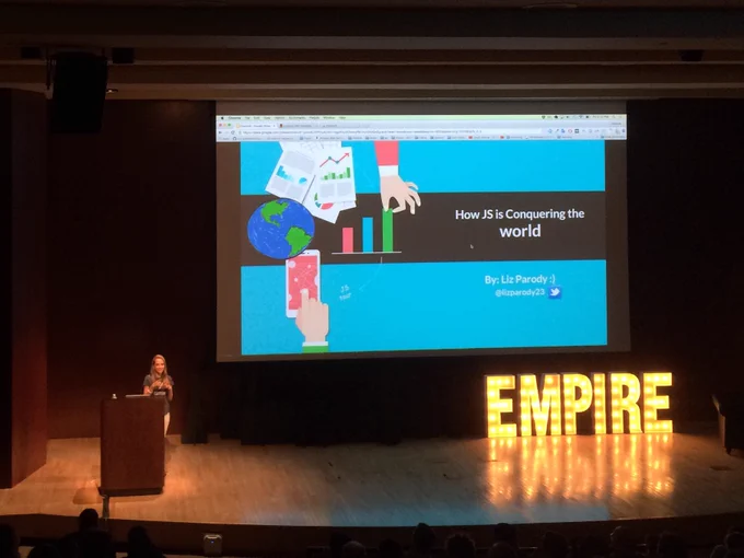 Speaker Liz Parody on stage with the first slide in her talk entitled "How JS is Conquering the World"