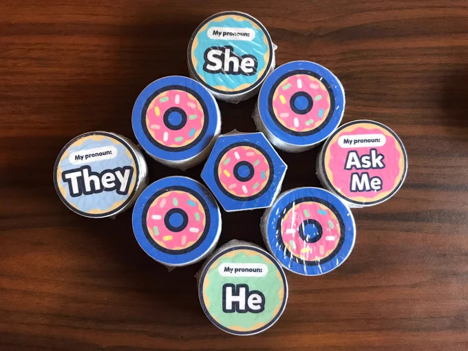 Stacks of round and hexagonal donut stickers and several pronoun stickers (Ask Me, He, She, They)