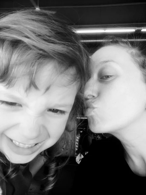 mother kissing her ginning daughter