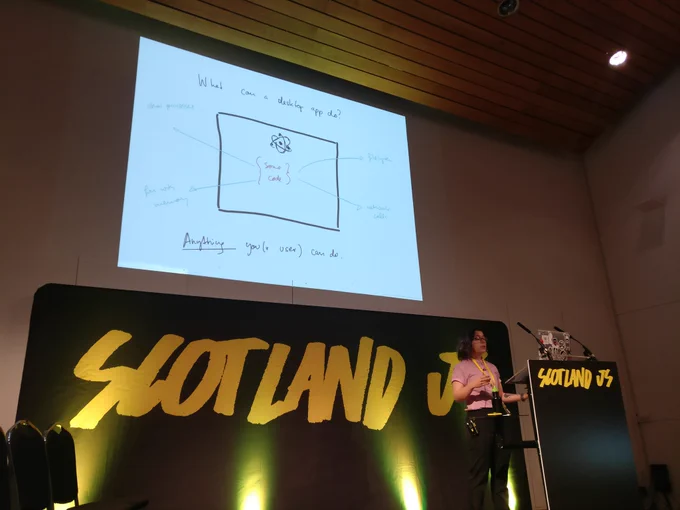 Flo on stage with screen saying with electron, the app can do anything you as a user can do on your machine.