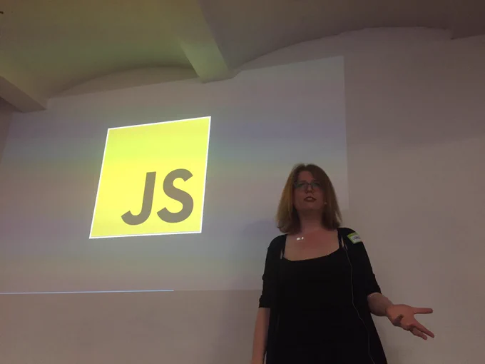 Charlie speaking in front of a slide with the JS logo.
