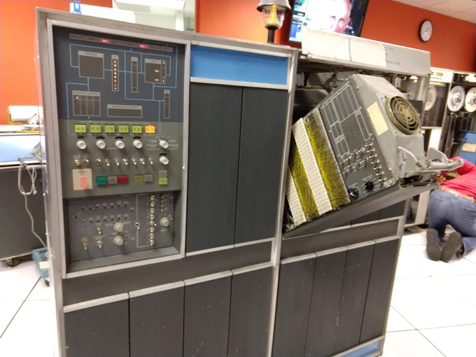 The IBM 1401 computer has a console with lights and buttons. On the right, the tape control unit (TAU) swings out of the computer to access tape controls.