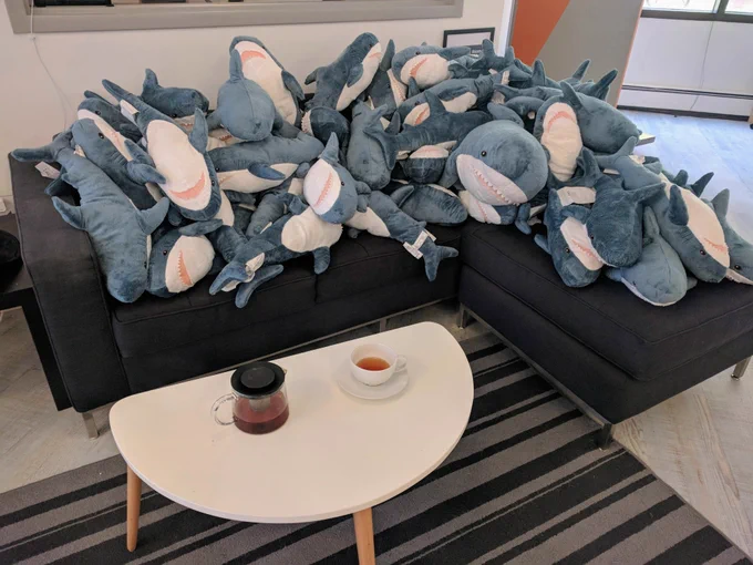 a pile of 50 plush sharks on a couch