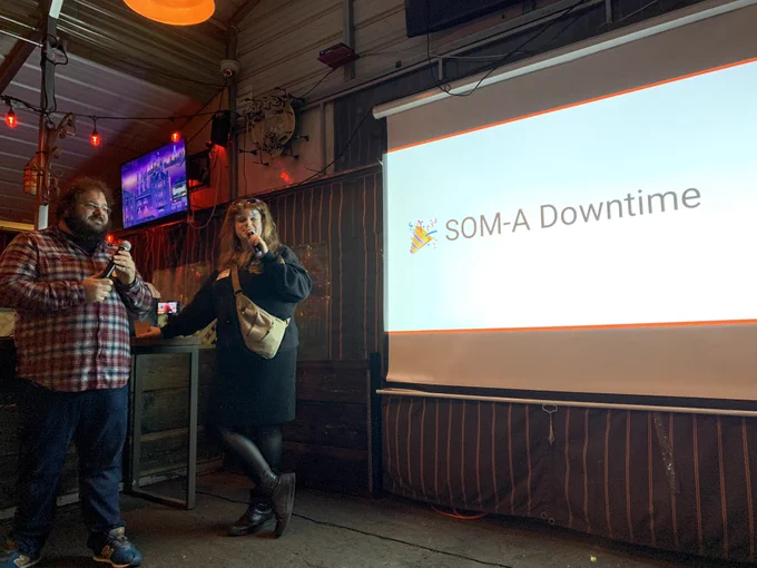 Emily and Potch in front of a slide that says “SOM-A Downtime”