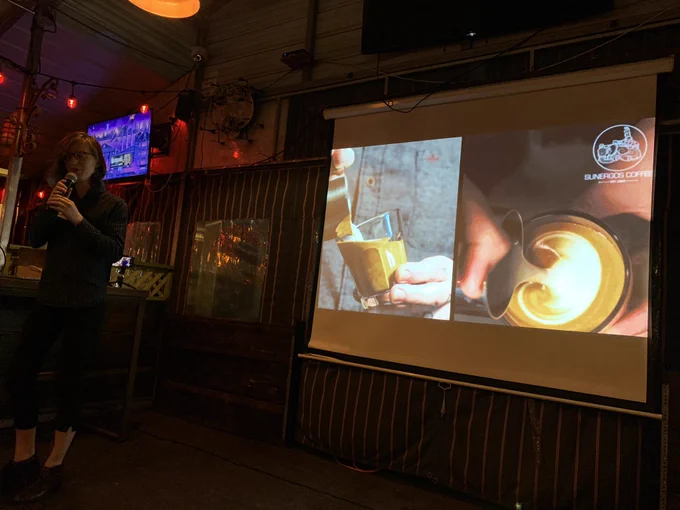 Picture of Max in front of a slide showing a barista pouring cream into espresso