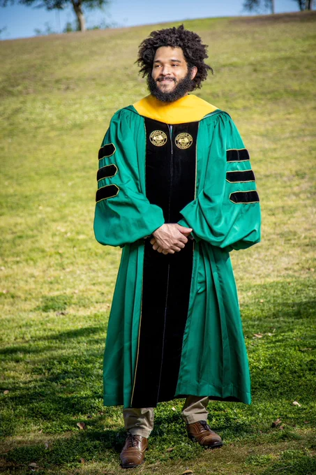 Photo standing in MSU PhD Regalia in grass field.