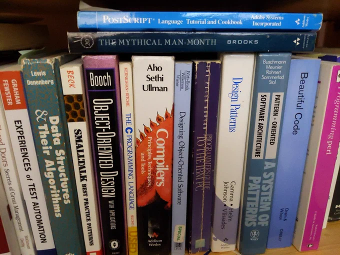 Close-up of a shelf of computer books. Authors: Grady Booch, Aho Sethi and Ullman, Fred Brooks, Larry Wall and Randal Schwartz, Gamma Helm Johnson and Vlissides, Kent Beck, Peter Norton.