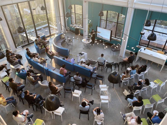 Overhead shot of Lazar Nikolov presenting to a room of seated TJS community members