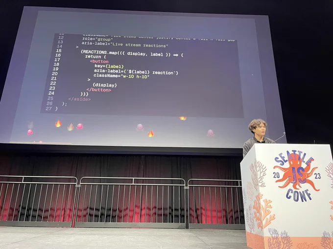 John on stage. emojis are flying across the bottom of the slides