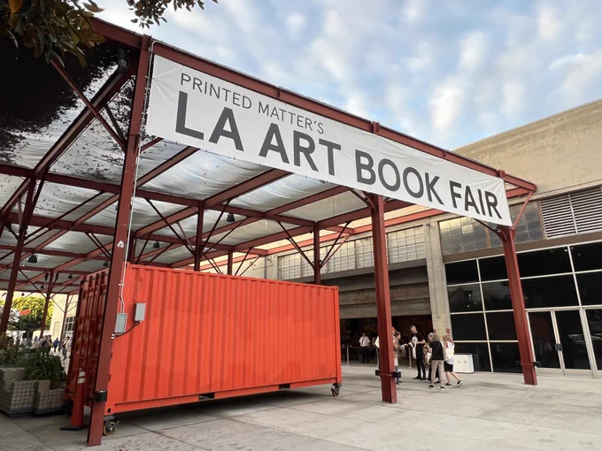 la art book fair banner hangs over moca building and an orange crate