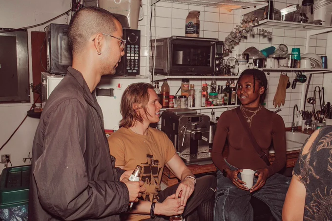 An image of three people talking to each other. They are sitting down and holding different beverages in their hands.