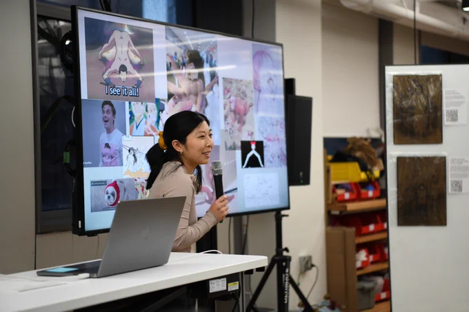 An image of Rachel Lim holding a mic next to a big t.v. screen that has funny memes and images she gathered. 
