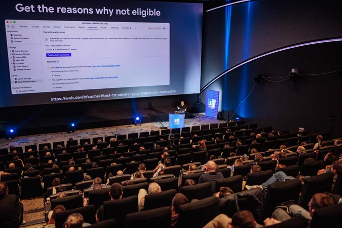 A further away shot of the talk and attendees from behind with me still going on and on about DevTools back/forward cache tester.