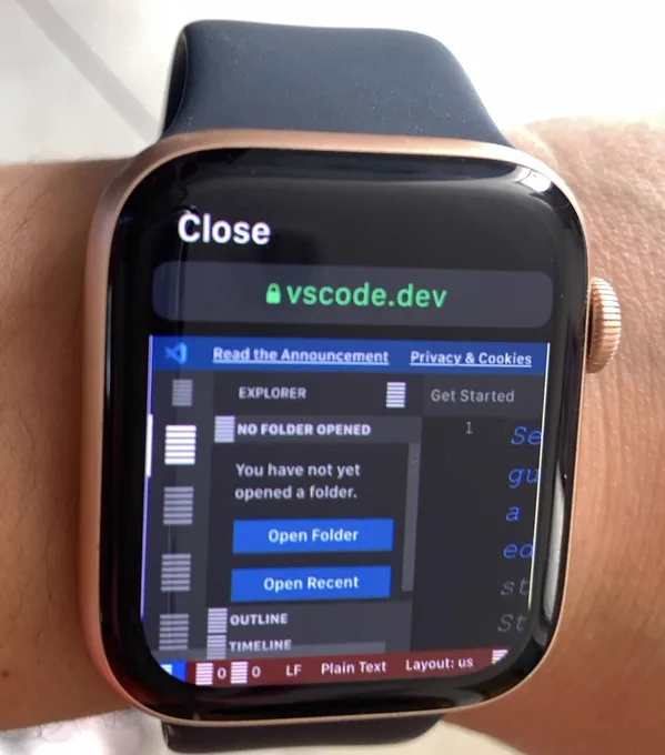Picture of a smartwatch that has a browser winner window open to vsco.dev and it's showing a file explorer next to a window used for editing code