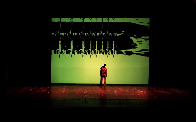 Scena di teatro con Re di spalle al centro. Fondale digitale astratto. 