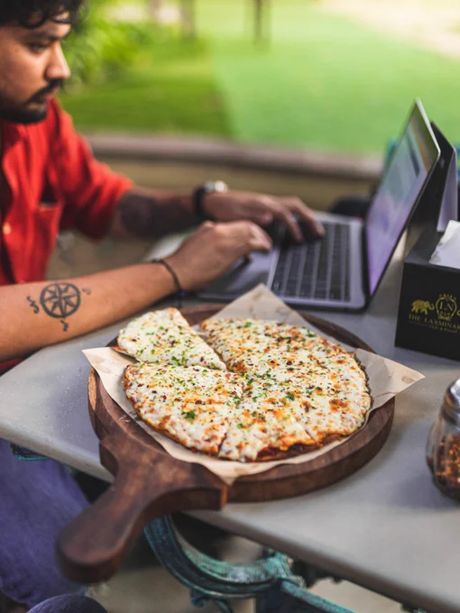Photo by Jay Gajjar on Unsplash. Man typing on laptop with pizza in foreground.
  