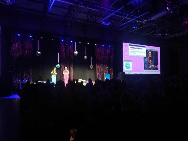 Me on stage with lots of people watching and my photo on the screen