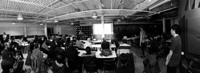 A black and white photo of a Room full of attendees for a presentation at a JavaScript meetup