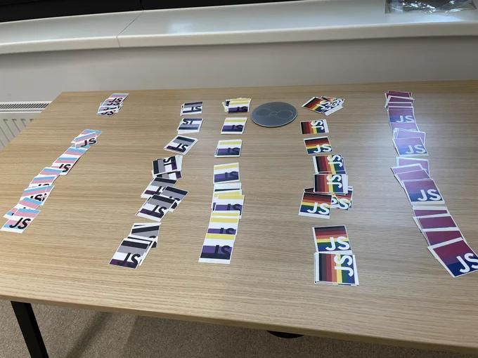 Stickers on a table with QueerJS flags on them