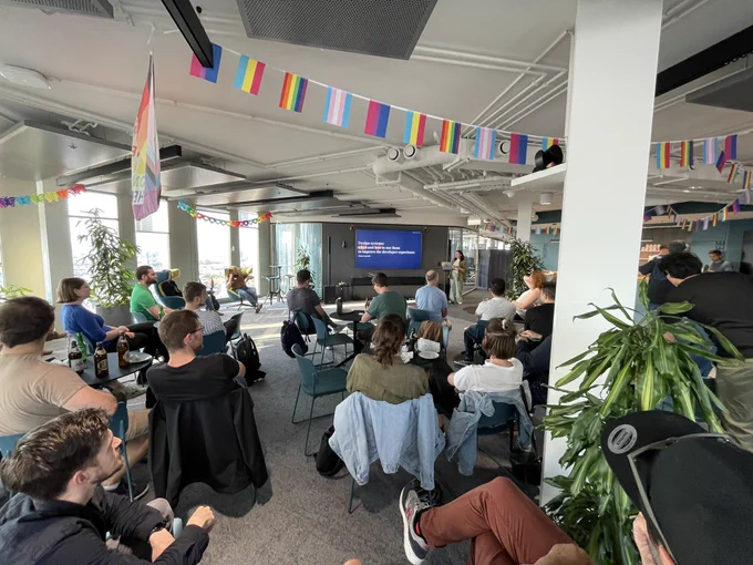 Elena Coazzoli giving a talk at the Vienna React Meetup and a room full of people listening to the talk.
