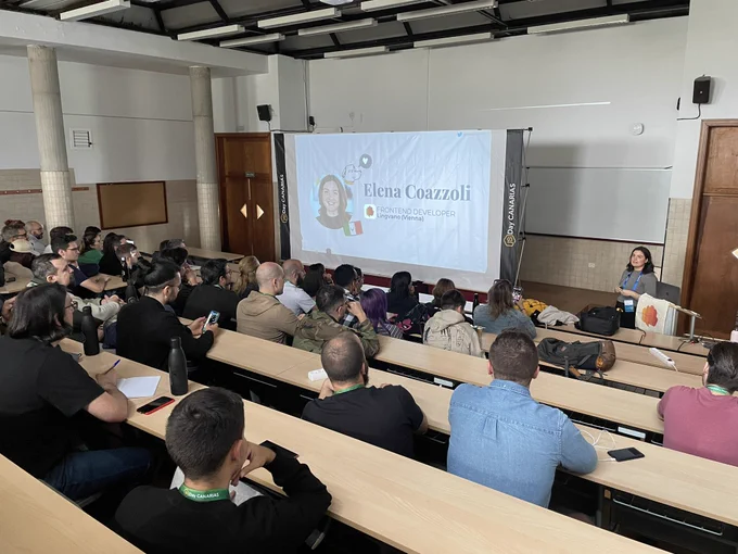 Elena Coazzoli giving a talk at the JSDayCanarias and a room full of people listening to the talk.