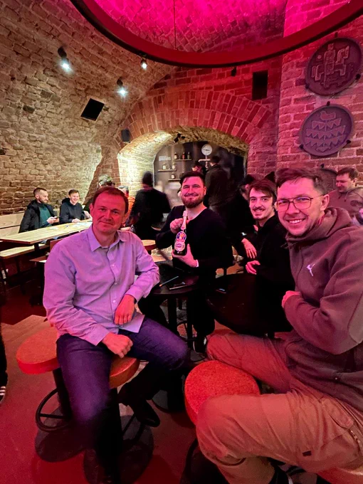 A group of diverse individuals gathered in the pub, engaged in lively discussion and teamwork during the IT quiz