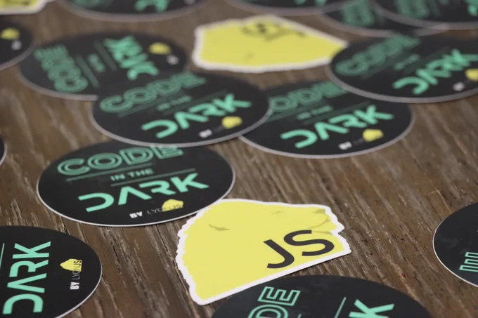 Photos of Code Ine The Dark and Lyon JS stickers on a table