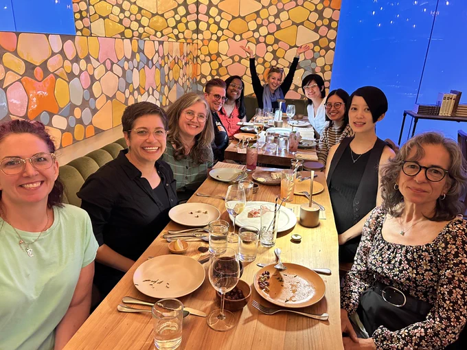 A group of educators sitting at a long table smiling to the camera