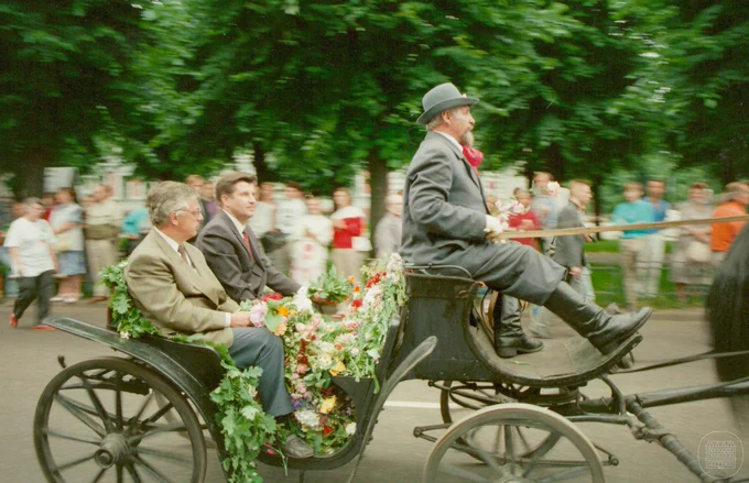 Latvijas Republikas Augstākās padomes priekšsēdētājs Anatolijs Gorbunovs un Latvijas Republikas kultūras ministrs Raimonds Pauls zirga pajūgā Rīgas ielā XX Vispārējo latviešu Dziesmu un X Deju svētku noslēguma gājiena laikā. 1990. gada 8. jūlijs. Fotogrāfs Leons Balodis. LNVM krājums.